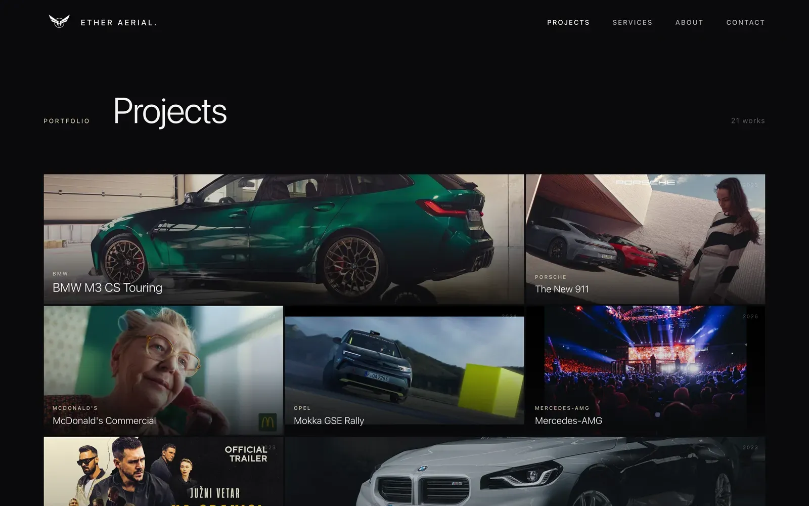 The Ether Aerial projects index on desktop: a dark page headed Projects with a mosaic of film stills, among them a green BMW, a close-up portrait and a rally car.